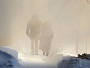 Two people are engulfed in exhaust from a high rise building while walking on a sidewalk in downtown Winnipeg on Wednesday. Chris Procaylo/Winnipeg Sun