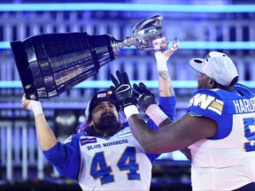 Shayne Gauthier #44 and Jermarcus Hardrick #51 of the Winnipeg Blue Bombers celebrate their victory with the Grey Cup following the 108th Grey Cup CFL Championship Game against the Hamilton Tiger-Cats at Tim Hortons Field on December 12, 2021 in Hamilton, Ontario, Canada.  (Photo by Vaughn Ridley/Getty Images)