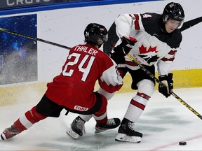 Team Canada's Carson Lambos (4) battles Team Austria's Lucas Thaler (24) during first period IIHF World Junior Hockey Championship action in Edmonton on Tuesday, Dec. 28, 2021.