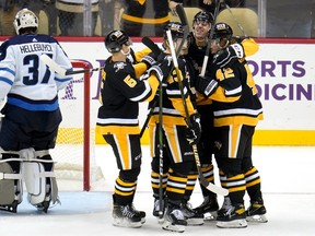 Pittsburgh Penguins' Kasperi Kapanen (42) celebrates his goal with teammates as Winnipeg Jets goaltender Connor Hellebuyck (37) collects himself during Sunday's game.