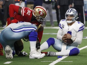 Dallas Cowboys quarterback Dak Prescott, right, holds the ball after recovering his own fumble on a sack by San Francisco 49ers defensive end Charles Omenihu (92) during the second half of an NFL wild-card playoff football game in Arlington, Texas, Sunday, Jan. 16, 2022.