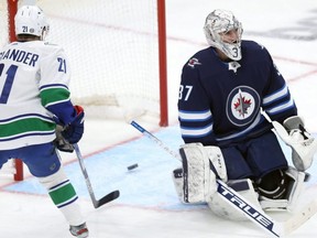Jets goalie Connor Hellebuyck (right) reacts after giving up a goal in a 5-1 loss to the Vancouver Canucks.