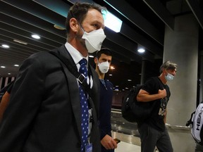 Serbian tennis player Novak Djokovic, centre, walks in Melbourne Airport before boarding a flight, after the Federal Court upheld a government decision to cancel his visa to play in the Australian Open, January 16, 2022.
