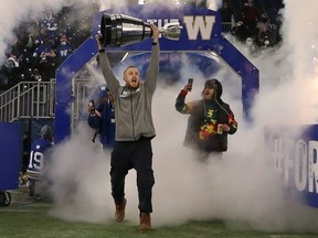Nick Hallett (centre) holds the Grey Cup high as the Winnipeg Blue Bombers celebrated its 2021 Grey Cup win at IG Field on Wednesday, Dec. 15, 2021.