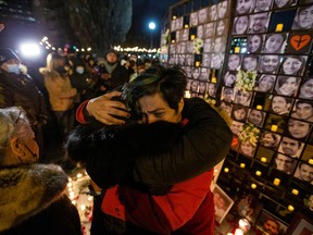 Mourners embrace as they attend an outdoor vigil for the victims of Ukrainian passenger jet flight PS752 which was shot down two years ago over Iran, in Toronto on January 8, 2022.