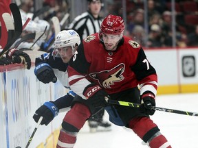 Winnipeg Jets center Kristian Reichel (87) and Arizona Coyotes defenceman Kyle Capobianco (75) battle for a puck during the first period at Gila River Arena in Glendale, Ariz., on Jan. 4, 2022.