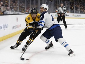 Winnipeg Jets defenceman Neal Pionk (4) tries to ride Boston Bruins right wing David Pastrnak (88) off the puck during the first period at TD Garden in Boston on Jan. 22, 2022.