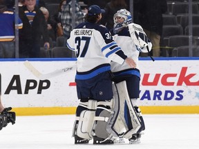 Winnipeg Jets goaltender Connor Hellebuyck (37) and Winnipeg Jets goaltender Eric Comrie (1) celebrate their teams victory after beating the St. Louis Blues at Enterprise Center in St. Louis on Jan. 29, 2022.