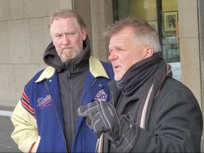 Jeff Chapman (left) listens as Karl Krebs addresses a group of approximately 15 people connected to Action4Canada in the courtyard of Winnipeg City Hall on Friday regarding a perceived loss of freedom in Canada during the pandemic. The group showed up at City Hall to serve “notices of liability” to elected officials and City executives.