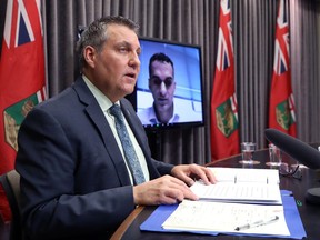 Education Minister Cliff Cullen speaks with Dr. Jazz Atwal listening via video conferencing during a press conference on the return to school, at the Manitoba Legislative Building in Winnipeg, on Tuesday, Jan. 4, 2022.