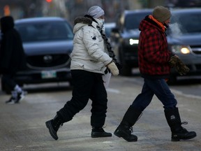 People crossing a busy street in Winnipeg during extreme cold on Friday. Jan. 7, 2022.