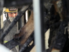 A firefighter looks at a burned structure in the backyard of a house in the 900 block of Alfred Avenue in Winnipeg on Thurs., Jan. 6, 2022. The building was fully engulfed when crews arrived. Occupants of the structure and house self-evacuated, with one sent to hospital in stable condition. The cause of the fire is under investigation and no damage estimate was available.  KEVIN KING/Winnipeg Sun/Postmedia Network