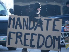 A person carries a sign near where a small number of people participated in an anti-government, roadside protest West of Winnipeg on Tuesday.