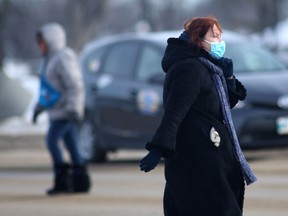 A person wears a mask while crossing a street in Winnipeg on Friday, Jan. 28, 2022.