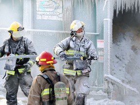 Firefighters with water spray frozen to their equipment battle a blaze at a pallet manufacturing company on Pandora Avenue West in Winnipeg on Wed., Jan. 5, 2022.  KEVIN KING/Winnipeg Sun/Postmedia Network