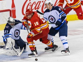 Winnipeg Jets goalkeeper Connor Hellebuyck and Neal Pionk against Calgary Flames Matthew Tkachuk during the first period of NHL action at Scotiabank Saddledome on Monday, February 21, 2022.