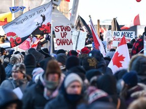 Protesters near Parliament Hill hold signs condemning the vaccine mandates imposed by Canadian Prime Minister Justin Trudeau on February 5, 2022 in Ottawa, Canada.