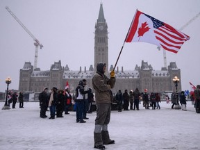 A demonstrator holds a U.S. and Canadian flag during a protest by truck drivers over COVID-19 mandates, outside the parliament of Canada in Ottawa on February 12, 2022.