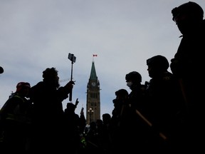 Canadian police officers stand guard in front of protesters, as they work to restore normality to the capital while trucks and demonstrators continue to occupy the downtown core for more than three weeks to protest against pandemic restrictions in Ottawa, on Feb. 19, 2022.