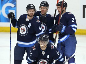 Jets centre Mark Scheifele (bottom) heads to the bench to celebrate one of his three goals against the Minnesota Wild in Winnipeg on Wednesday night.