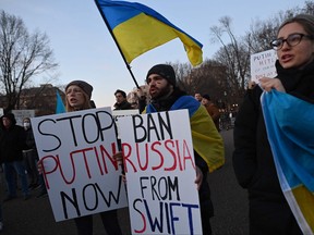 Activists protest against Russias invasion of Ukraine and hold a sign reading "Ban Russia From SWIFT" during a rally at Lafayette Square, across from the White House, in Washington, D.C. on Feb. 25, 2022.