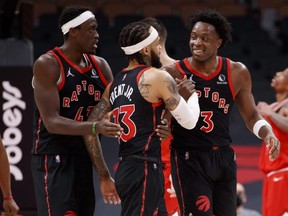 Pascal Siakam (left) and OG Anunoby (right) of the Toronto Raptors celebrate a three-point basket by Gary Trent Jr. (centre) during an NBA game on Feb. 3, 2022.