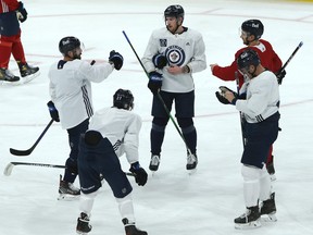 Pierre-Luc Dubois (centre) and Neal Pionk right), discussing power-play strategy at a recent practice, will both be back Friday night in Dallas after missing one game apiece.