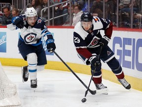 Colorado Avalanche center Nathan MacKinnon (29) controls the puck ahead of Winnipeg Jets defenceman Neal Pionk (4) in the second period at Ball Arena in Denver on Feb. 25, 2022.