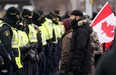 Police officers deploy to move protesters blocking access to the Ambassador Bridge and demanding an end to government COVID-19 mandates, in Windsor, Ont., on Saturday, Feb. 12, 2022.