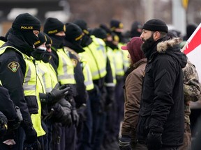 Police officers deploy to move protesters blocking access to the Ambassador Bridge and demanding an end to government COVID-19 mandates, in Windsor, Ont., on Saturday, Feb. 12, 2022.