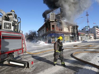 A firefighter walks by as a blaze rips through a historic building at the northwest corner of Langside Street and Portage Avenue in Winnipeg on Wed., Feb. 2, 2022.  KEVIN KING/Winnipeg Sun/Postmedia Network