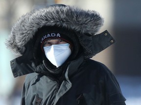 A person wears a mask while walking along a sidewalk in Winnipeg on Friday, Feb. 11, 2022.