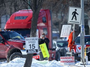 One person stands among illegally parked vehicles and miscellaneous signs in Winnipeg on Friday, Feb. 11, 2022.