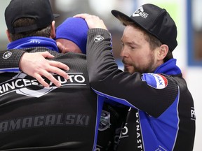 Mike McEwen (right) and Derek Samagalski (left) celebrate a provincial men's curling championship win with an emotional Colin Hodgson at the Selkirk Curling Club in Selkirk on Sunday, Feb. 13, 2022.