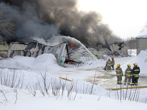 Crews tackle a fire at a vacant warehouse on Point Douglas Avenue in Winnipeg on Monday. A front-end loader was needed to clear a path through deep snow to get crews in.