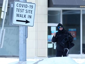 A person stands near a sign for a COVID-19 test site in Winnipeg on Wednesday.  Chris Procaylo/Winnipeg Sun