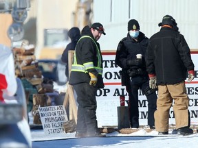 A Winnipeg Police officer talks with a group of individuals who are occupying streets around the Manitoba Legislative Building in Winnipeg on Thursday, Feb. 17, 2022.