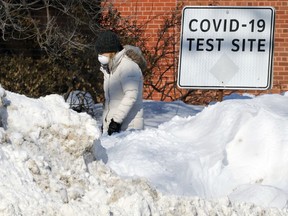 A woman wearing a mask passes a sign outside the COVID-19 testing site on St. MaryÕs Road in Winnipeg on Wed., Feb. 23, 2022.  KEVIN KING/Winnipeg Sun/Postmedia Network