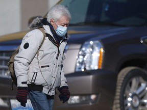 A person wears a mask while crossing a street in downtown Winnipeg on Friday, Feb. 25, 2022.