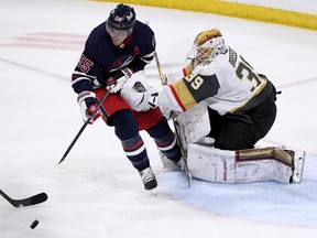 Winnipeg Jets' Mark Scheifele looks to get the loose puck as Vegas Golden Knights goaltender Laurent Brossoit  pushes him during second period NHL action in Winnipeg on Tuesday March 15, 2022.