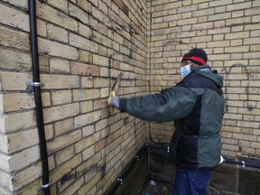 Anti-Semitic, homophobic and lewd graffiti was spray-painted on the rear walls on the Metropolitan United Church on Queen St. East at Church St. over the weekend. (Pictured) A church worker uses a power washer, solvents and a wire brush to remove the graffiti.  on Tuesday March 8, 2022.