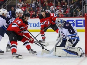 Winnipeg Jets goaltender Eric Comrie makes a save on New Jersey Devils centre Jack Hughes last night.  USA TODAY SPORTS