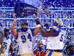 Jackson Jeffcoat #94 and Jermarcus Hardrick #51 of the Winnipeg Blue Bombers celebrate victory with the Grey Cup following the 108th Grey Cup CFL Championship Game against the Hamilton Tiger-Cats at Tim Hortons Field on December 12, 2021 in Hamilton, Ontario, Canada.