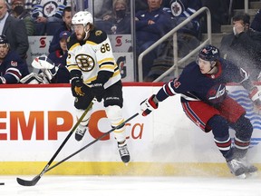 Boston Bruins right wing David Pastrnak (88) jumps as the puck is eyed by Winnipeg Jets defenceman Logan Stanley (64) in the first period at Canada Life Centre in Winnipeg on Friday, March 18, 2022.