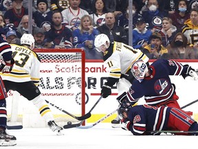 Boston Bruins center Trent Frederic (11) scores on Winnipeg Jets goaltender Connor Hellebuyck (37) in the second period at Canada Life Centre in Winnipeg on Friday, March 18, 2022.