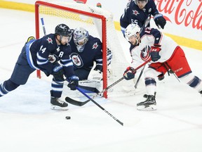 Winnipeg Jets goalie Eric Comrie (1) stops Columbus Blue Jackets forward Justin Danforth (17) during the third period at Canada Life Centre in Winnipeg on Friday, March 25, 2022.