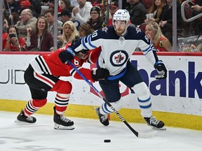 Pierre-Luc Dubois (80) of the Winnipeg Jets maintains control of the puck as Jake McCabe (6) of the Chicago Blackhawks defends in the third period on March 20, 2022 at the United Center in Chicago. Winnipeg defeated Chicago 6-4.