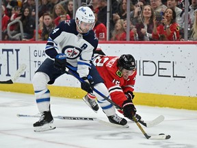 Josh Morrissey (44) of the Winnipeg Jets battles for control of the puck with Alex DeBrincat of the Chicago Blackhawks in the second period on March 20, 2022 at the United Center in Chicago.