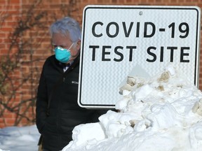 A man wearing a mask walks past a sign at the COVID-19 testing site on St. MaryÕs Road in Winnipeg on Wed., March 2, 2022.  KEVIN KING/Winnipeg Sun/Postmedia Network
