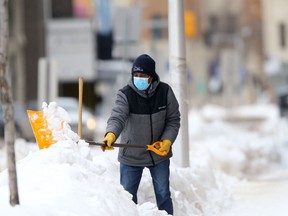 A person wears a mask while shovelling snow in downtown Winnipeg.   Chris Procaylo,  Friday. March 04. 2022 Winnipeg Sun.